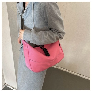 Detail of pink nylon dumpling bag showing adjustable black strap and crossbody styling