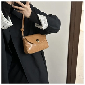 Mirror selfie showing a brown faux leather shoulder bag with a gold round twist lock