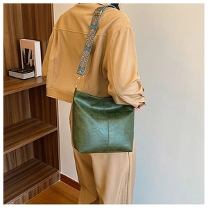 Detail of vintage green bucket bag with bohemian embroidered wide shoulder strap