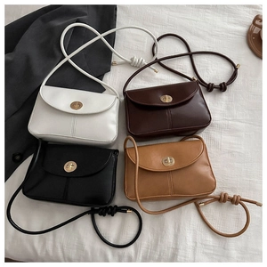 Detail view of four vintage crossbody bags with gold rotary buckles on white fabric