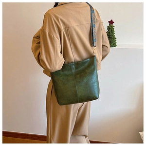 Detail of dark green vintage bucket bag with ethnic embroidered wide shoulder strap