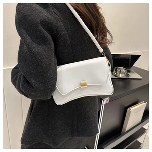 Detailed close-up of white leather baguette bag with premium golden metal buckle