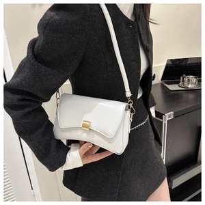 Close-up of white minimalist baguette bag with gold buckle on a model in office setting
