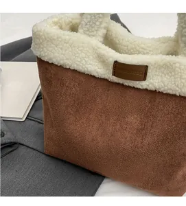 Detail of winter sherpa and suede tote bag with contrast stitching and leather brand tag