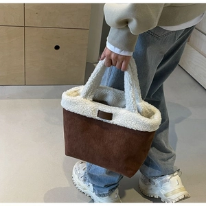 Detail of contrast stitching and texture on sherpa fleece and suede patchwork tote bag