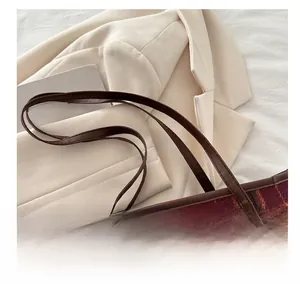 Close-up of the vintage red-brown plaid fabric and leather handle on this tote bag