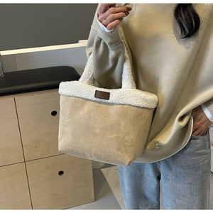 Close-up of lamb wool and suede tote bag carried by a model in a minimalist room