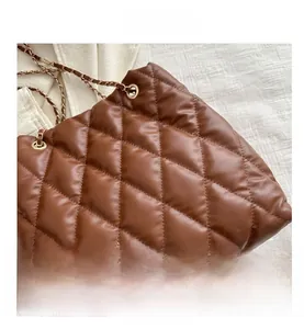 Close-up of quilted brown leather tote bag texture with gold chain strap detail