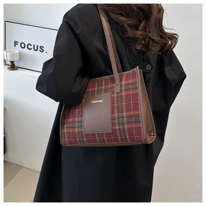 Detail showing red and green plaid tweed texture on a stylish autumn tote bag