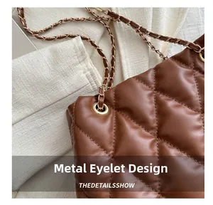 Detail of brown quilted bucket bag featuring metal grommets and chain shoulder strap