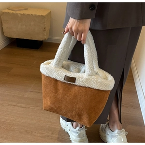 Detail of the sherpa wool and caramel suede bucket bag with leather brand logo
