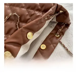 Detail of gold metal magnetic buckles and leather-interwoven chain on dark brown bucket bag