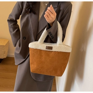 Close-up of contrast faux shearling tote bag with brown suede base and logo patch