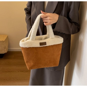 Close-up of brown suede handbag with white faux shearling trim and leather patch
