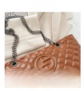 Macro shot of brown quilted leather shoulder bag with circular logo and metal chain