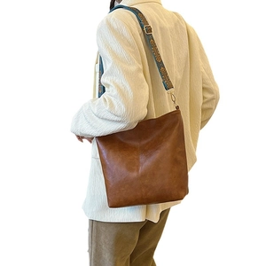 Brown leather tote bag with vintage bohemian pattern strap shown on model's shoulder