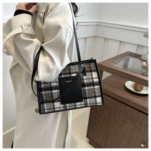 Detail of plaid tweed tote bag showing black leather strap and textured woven fabric