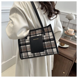 Close-up of plaid tweed tote bag with leather pocket and gold FASHION & BAGS lettering