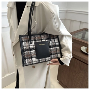 Detail view of plaid tweed tote bag with leather pocket and slim handles on model
