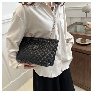 Macro detail of black quilted tote bag with chain strap and embossed circular logo