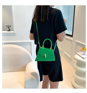 Détail d'un mini sac à main trapèze vert vif porté en bandoulière sur une tenue moderne