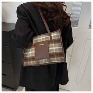 Detail of British plaid tote bag featuring green and brown woven fabric and leather straps
