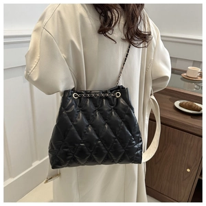 Detail of black quilted bucket bag featuring elegant gold chain strap and leather texture