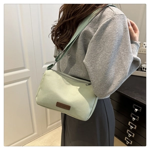 Vue latérale d'un sac bandoulière en nylon vert clair porté avec une sangle réglable