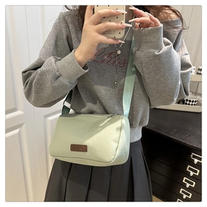 Détail du sac bandoulière en nylon vert clair avec sangle ajustable et empiècement mode