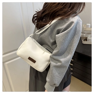Detailed side view of a white PU leather crossbody bag worn by a model in a modern room