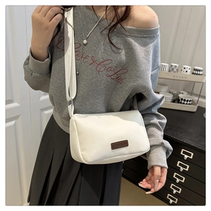 Détail d'un sac bandoulière en nylon blanc avec un écusson Fashion en cuir marron