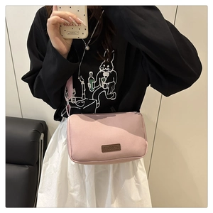 Vue détaillée du sac bandoulière rose avec étiquette de mode et sangle assortie