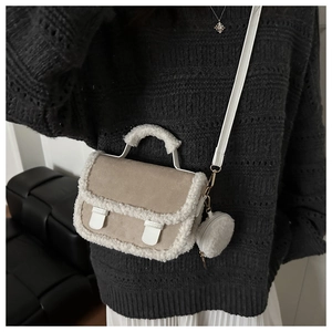 Detail of khaki plush crossbody bag with sherpa trim worn over a grey knit sweater