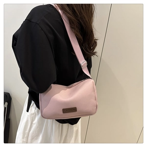 Pink waterproof crossbody bag with adjustable strap and fashion label detail on a model