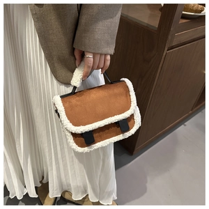 Detail of brown suede crossbody bag with plush faux shearling trim and buckle