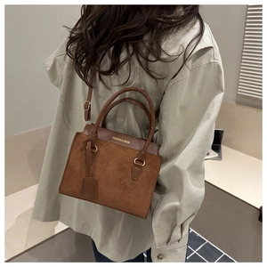 Gros plan du sac bandoulière caramel avec texture daim et texte mode sur modèle