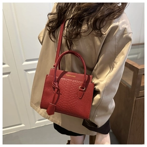 Macro shot of red crocodile embossed leather tote with elegant gold lettering detail