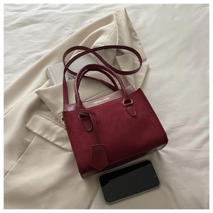 Détail du sac à main bordeaux en cuir et suède avec lettrage doré et smartphone