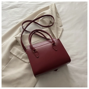 Detailed close-up of dark red crossbody bag on cream blazer and white fabric