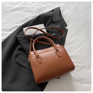 Macro view of brown PU leather bag with vintage gold hardware on a black blazer