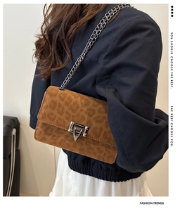 Close-up of leopard print crossbody bag with silver chain and metal twist lock