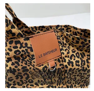 Makro-Detail der Leopard-Canvas-Tasche mit Leder-Markenetikett und Metallring-Akzent