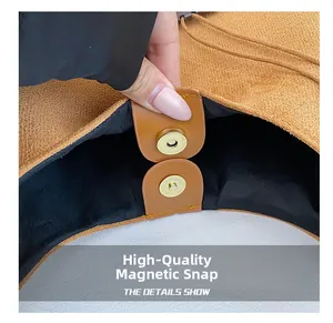 Gros plan sur le fermoir magnétique doré d'un sac cabas en daim marron de qualité