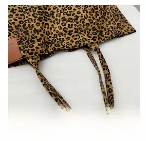 Detailansicht der verstärkten Leoparden-Griffe und braunem Lederlogo auf der Tasche