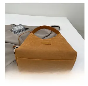 Détail d'un cabas en daim marron avec étiquette en cuir et texture douce au toucher