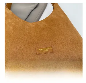 Gros plan sur le sac fourre-tout en daim marron avec écusson en cuir et détails de couture