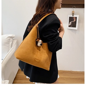 Détail du sac cabas en daim jaune gingembre avec un charmant pendentif chien en peluche