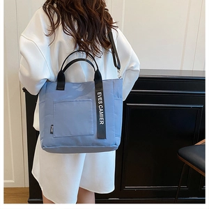 Detail of light blue canvas lunch bag with black handles and detachable shoulder strap