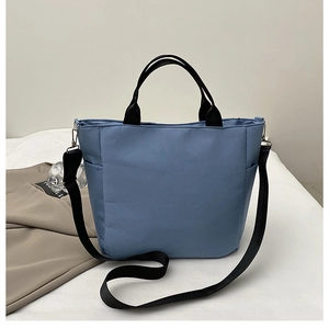 Détail du sac cabas bleu en tissu composite avec poignées noires et poche latérale