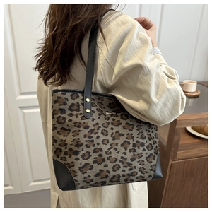 Close-up of leopard print tote bag with black leather straps and gold metal logo plate